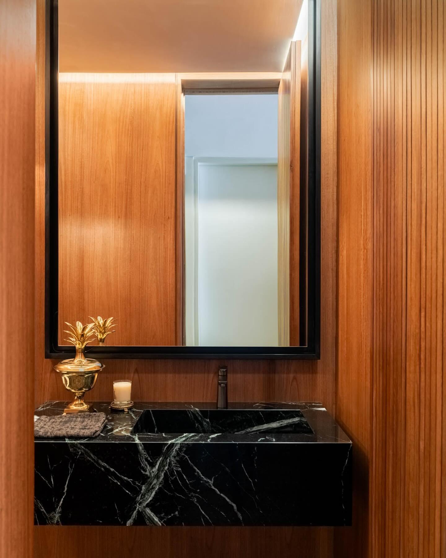Black marble basin against warm timber in Apartamento DB